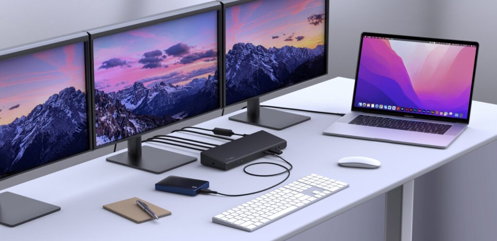 Biurko z laptopem podłączonym do dodatkowych monitorów i sieci przez stację dokującą USB-C.